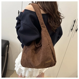 Detailed close-up of dark brown corduroy tote bag texture with fashion label on exterior pocket