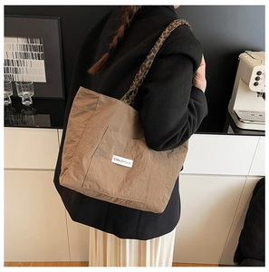 Détail du sac cabas kaki avec bandoulière léopard et écusson de marque sur le devant