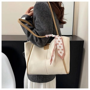 Close-up of off-white tote bag with brown trim and decorative pink polka dot silk scarf