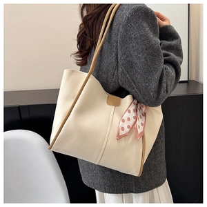 Close-up of beige leather tote bag with polka dot scarf and minimalist brown trim