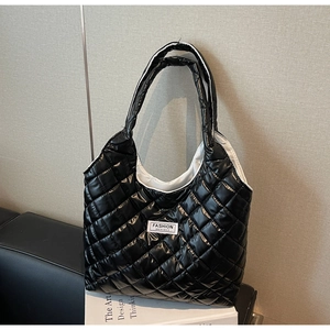 Detail of black quilted tote bag with white fashion label on shiny nylon material