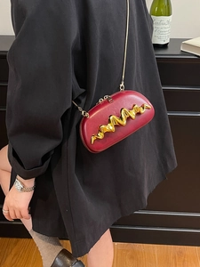 Borsa a tracolla ovale rossa con dettaglio onda dorata e catena indossata da modella