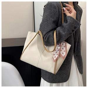Detail view of off-white tote bag with brown handles and a pink polka dot silk scarf