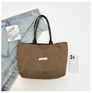 Détail macro du sac cabas en nylon marron foncé avec poignées léopard et poche externe
