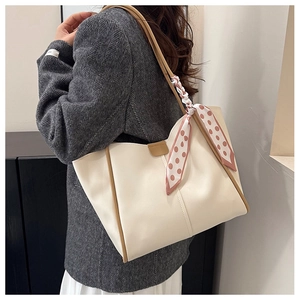 Detail of cream tote bag with brown trim and decorative polka dot scarf on the handle