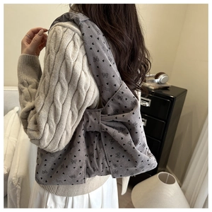 Detail of grey corduroy crossbody bag with large bow and black heart pattern