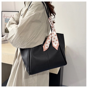 Detail of black lychee grain tote bag featuring a pink polka dot silk scarf handle accent