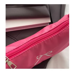 Close-up of a pink nylon bag featuring white bow embroidery and a silver metal zipper