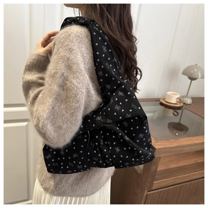 Detail of black corduroy tote bag with white heart patterns and large side bow ornament