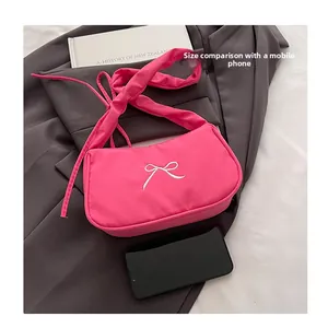 Pink fabric dumpling bag with bow embroidery shown next to a smartphone for size scale