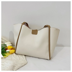 Close-up of minimalist cream tote bag with khaki trim and double handles on a cozy background