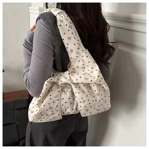 Detailed view of cream corduroy shoulder bag featuring heart print and a large bow design