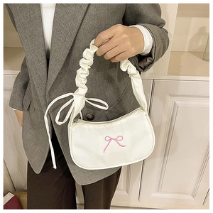 Detail of cream white pleated shoulder bag featuring elegant pink bow embroidery