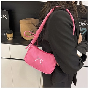 Detail of pink nylon underarm bag with bow embroidery and puffy strap on a model