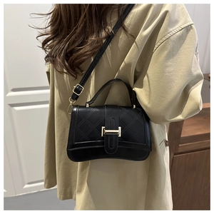 Side view of black quilted leather shoulder bag with gold metal buckle on a model