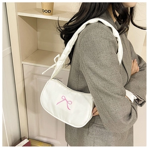 White crescent hobo bag with pink bow embroidery worn as a soft shoulder bag