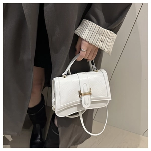 Detail of white quilted handbag with golden H buckle and textured synthetic leather