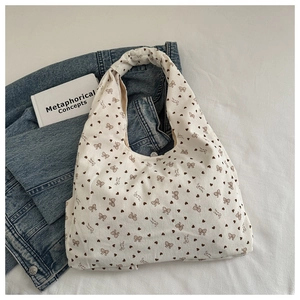 Detail of cream corduroy tote bag with brown heart and bow patterns on bed