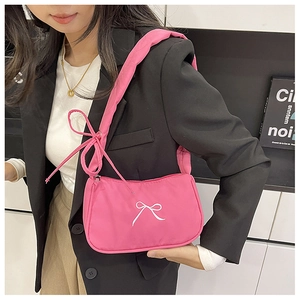 Model carrying a pink nylon shoulder bag with white bow embroidery and tie-knot strap