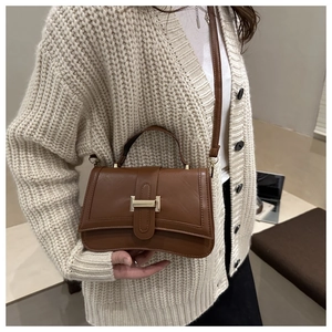Detail of brown quilted satchel bag showing hourglass curved bottom and gold metal buckle