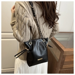 Close-up of black leather bucket bag featuring gold Fashion logo and chain strap