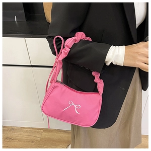 Detail of pink shoulder bag with white bow pattern and stylish scrunchie handle strap