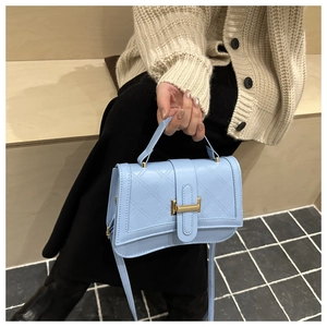 Macro view of light blue quilted leather handbag with gold clasp and top handle detail