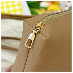 Detailed close-up of golden metal zipper and stitching on the khaki tote bag