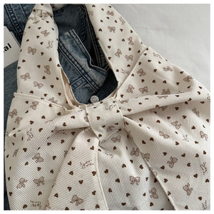 Detailed texture of off-white corduroy tote bag with brown heart and bow patterns