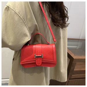 Detail of red quilted leather handbag with elegant metal hardware and crossbody strap