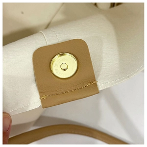 Detail of magnetic snap closure on canvas tote with brown leather trim and gold hardware