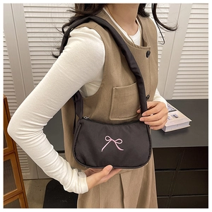 Detail of black nylon crescent bag with pink embroidered bows and puffy shoulder strap