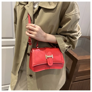 Detail of red quilted PU leather shoulder bag with gold clasp and elegant curved base