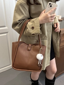 Brown leather shoulder bag with plush charm and decorative stitching for women