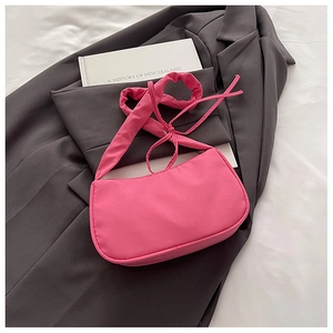 Detail view of pink nylon baguette bag placed on a grey blazer for a stylish look