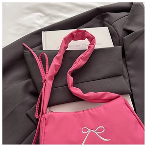 Detail of pink shoulder bag featuring white bow embroidery and ruffled strap design