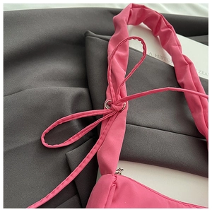 Detail of rose pink nylon shoulder bag showing ruched strap and drawstring bow decoration