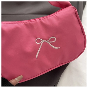 Close-up of pink nylon handbag featuring white embroidered bow and zipper detail