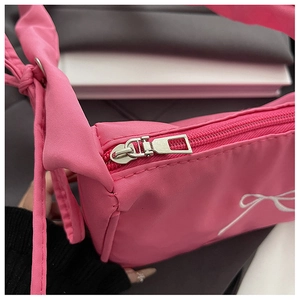 Detail of rose pink shoulder bag featuring white bow embroidery and knotted strap design