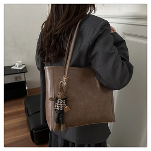 Detail of vintage brown leather tote bag with a cute rabbit charm and shoulder straps