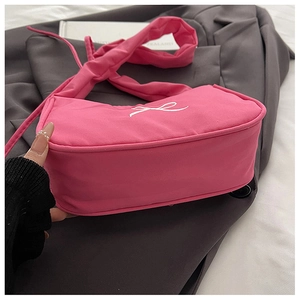 Detail of hot pink shoulder bag featuring white bow embroidery and knotted handle design