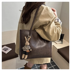 Brown leather tote bag featuring a cute rabbit charm detail on a minimalist shoulder strap