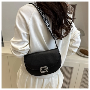 Dettaglio borsa a sella in pelle litchi nera con fibbia G e tracolla con motivi chic