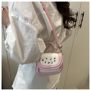 Dettaglio della borsa a tracolla rosa e bianca con motivo ciliegia su sfondo camicia