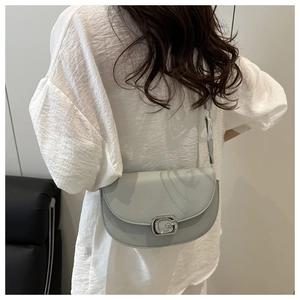 Detail of light grey lychee leather saddle bag with silver diamond G-shaped buckle