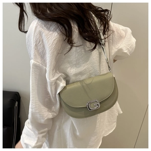 Sage green lychee leather saddle bag with diamond G buckle worn by a model