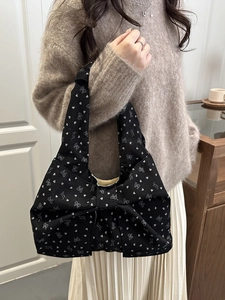 Stylish black shoulder bag with heart patterns and a large 3D bow decoration