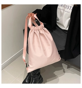 Detail view of pink nylon drawstring backpack showing the glossy texture and strap