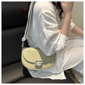 Detailed view of light green leather crossbody bag featuring a crystal G buckle and wide strap