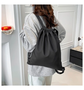 Detail of adjustable straps and buckle on a black nylon drawstring travel backpack